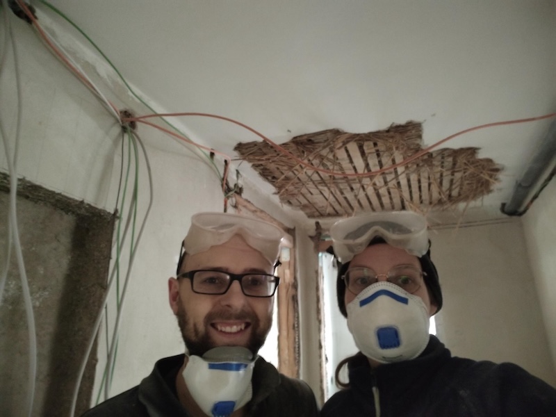 Two renovators in masks with exposed ceiling